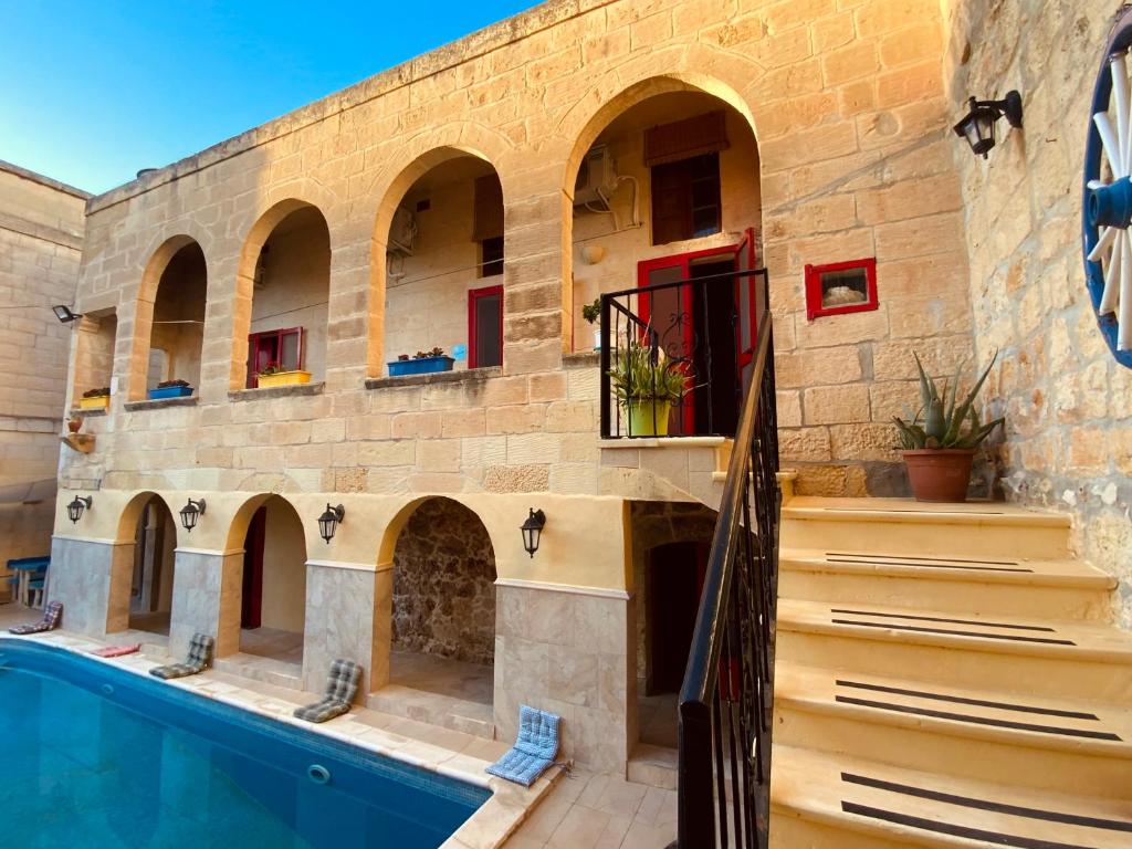 une maison avec une piscine et des escaliers à côté de celle-ci dans l'établissement Gozo Sunset Farmhouse, à Qala