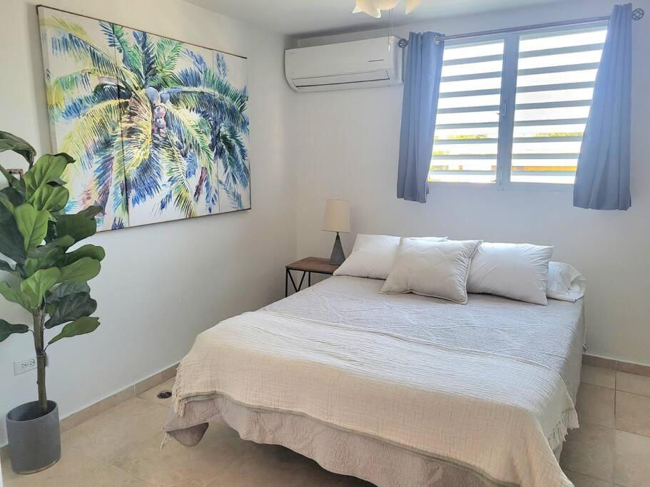 a bedroom with a bed and a palm tree painting on the wall at Steps to the Beach l Private Apt Stay l Parking WiFi Nightlife in San Juan