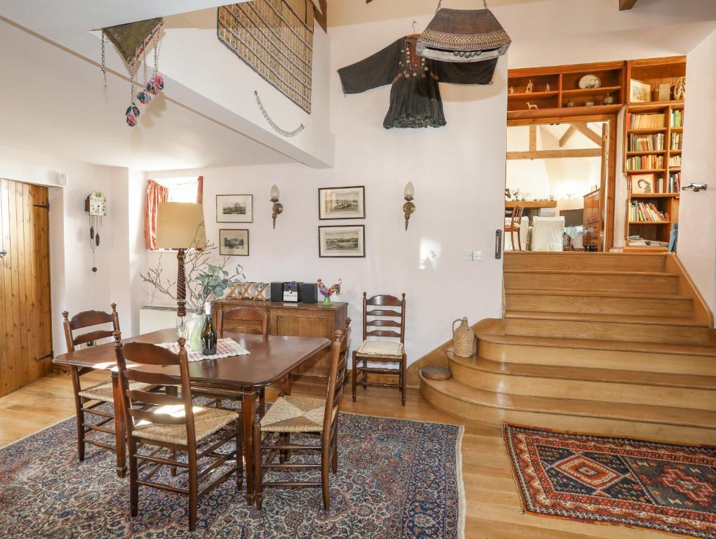 ein Esszimmer mit einem Tisch, Stühlen und einer Treppe in der Unterkunft Llo Bach in Abergele