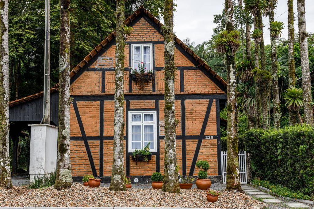une maison avec des arbres devant elle dans l'établissement Casa enxaimel em Pomerode, à Pomerode