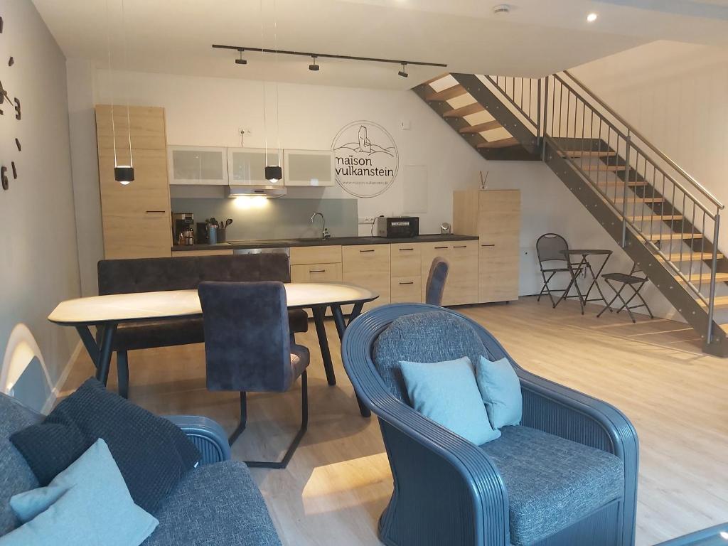 a living room with a table and chairs and a kitchen at Maison Vulkanstein in Landkern