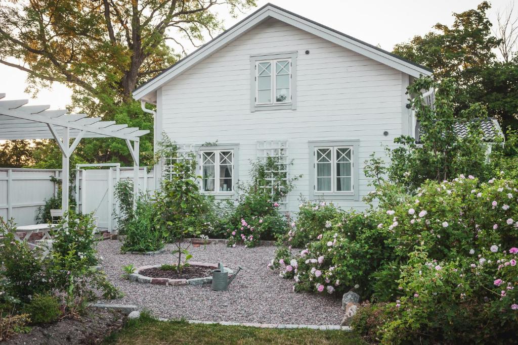 una casa blanca con un jardín delante de ella en Vallby Cottage en Enköping
