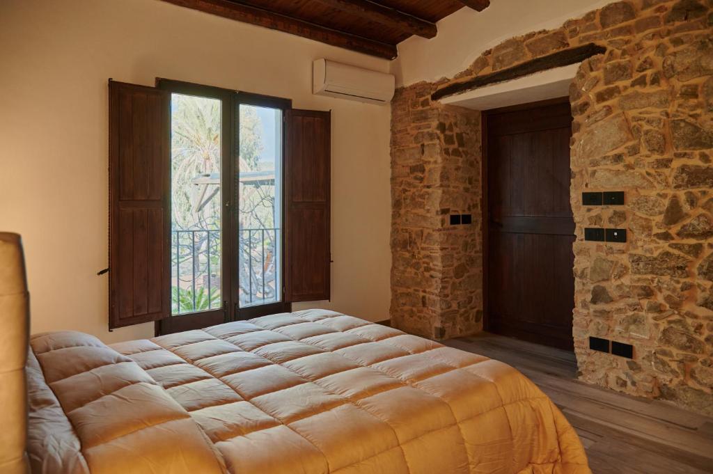 a bedroom with a large bed and a stone wall at Tenuta Luogo Marchese in Pollina
