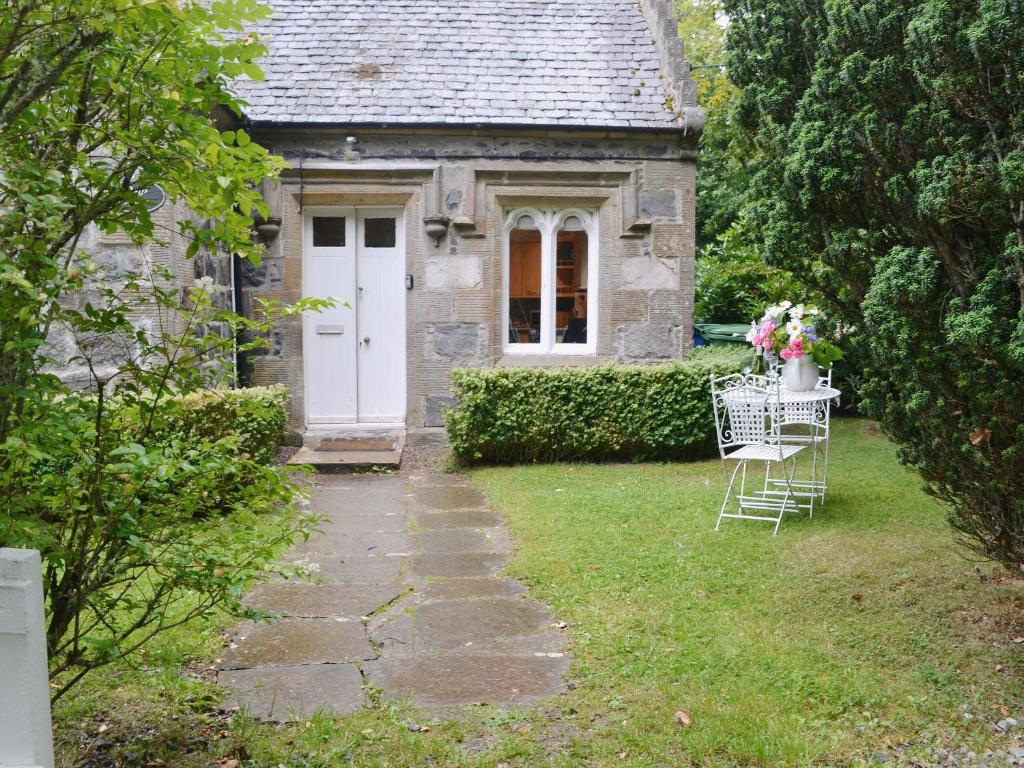 a small house with a white door and a table and chairs at Duffs Lodge - Beaufort Estate in Belladrum