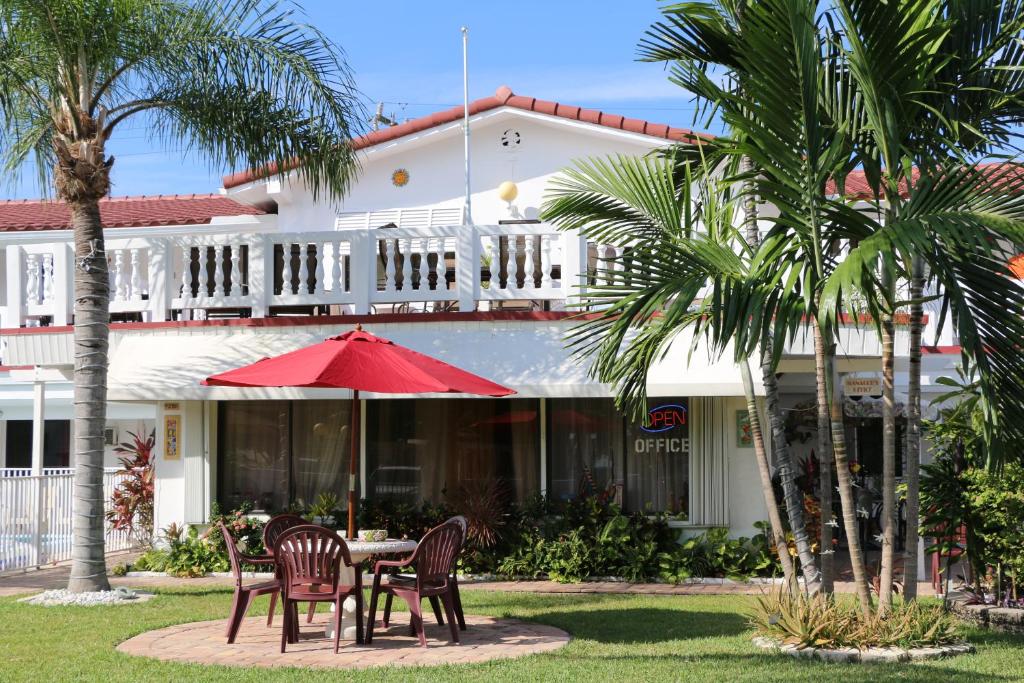 a table with chairs and an umbrella in front of a building at Breakaway Inn Guest House in Fort Lauderdale