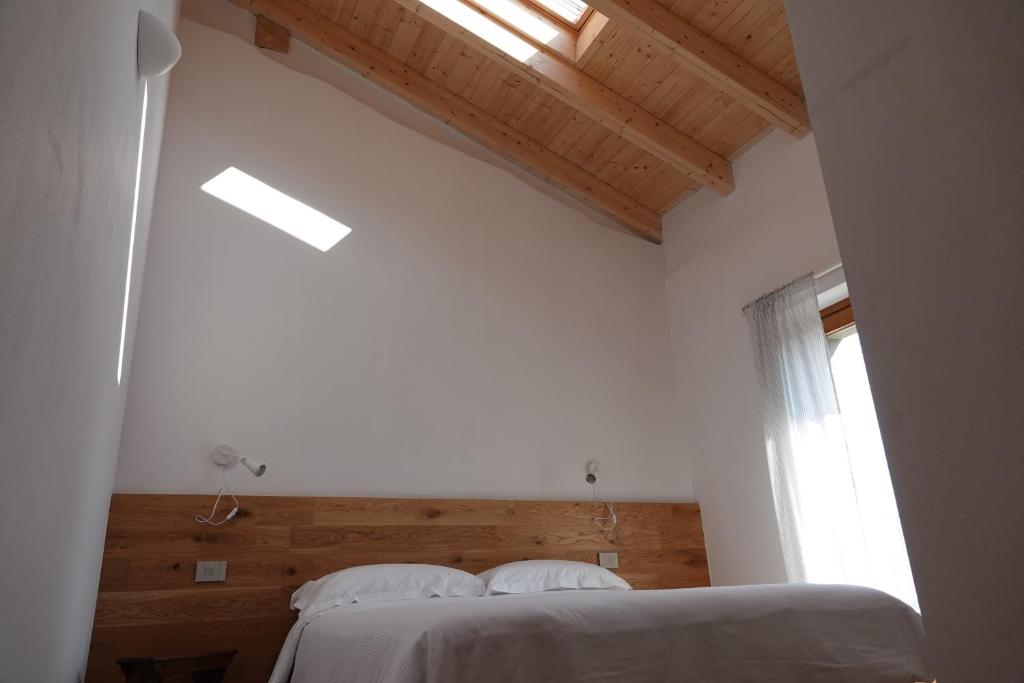 a bedroom with a bed in a white room with a window at Casale Bella.Vista in Pianello Del Lario