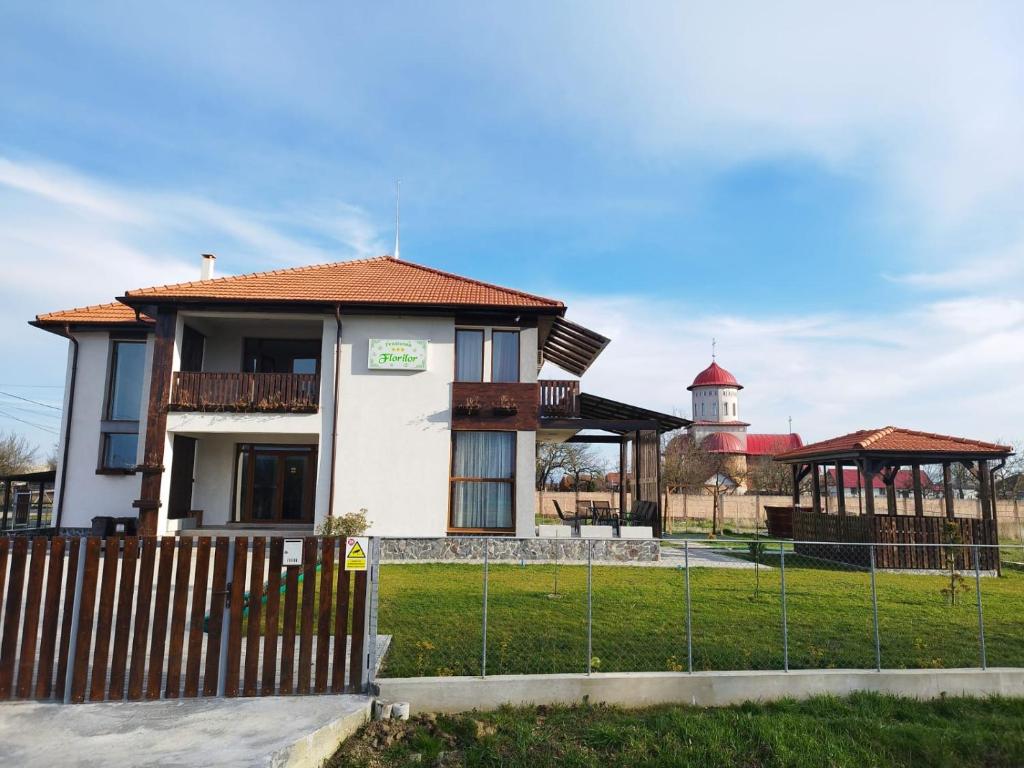 una casa con una recinzione e un faro sullo sfondo di Pensiunea Florilor Satu Mare a Satu Mare