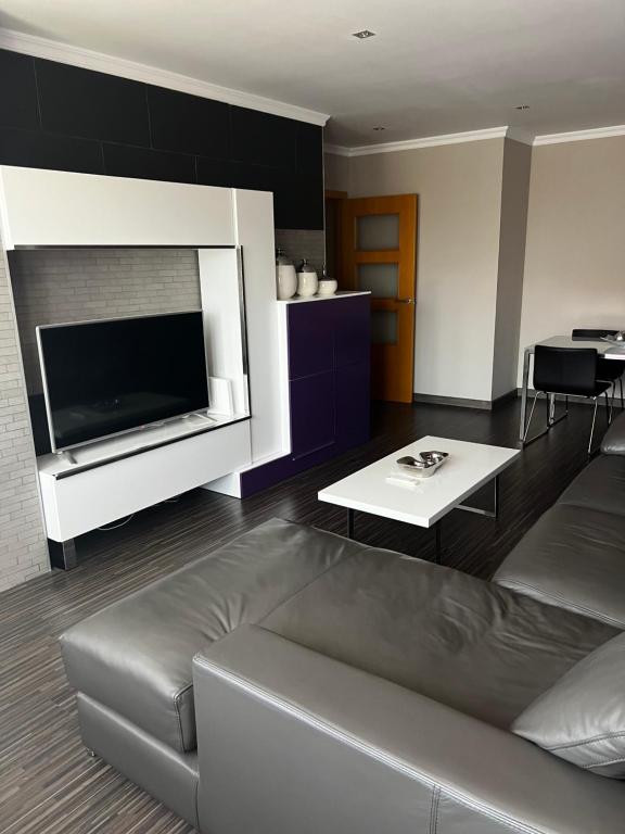 een woonkamer met een bank en een grote tv bij Casa del tiempo in Vecindario