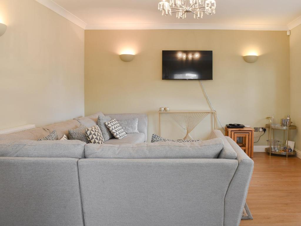 a living room with a couch and a television on the wall at The Lodge in Cosham