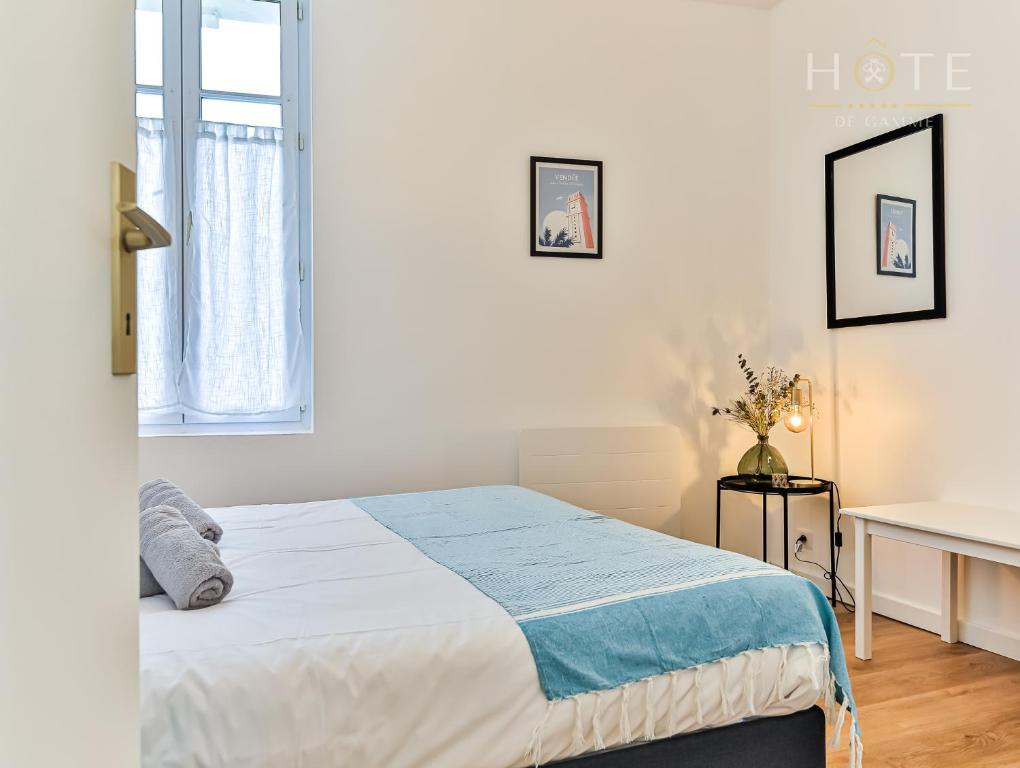 a white bedroom with a bed and a desk at Maison de surfeurs, idéalement située in Les Sables-dʼOlonne