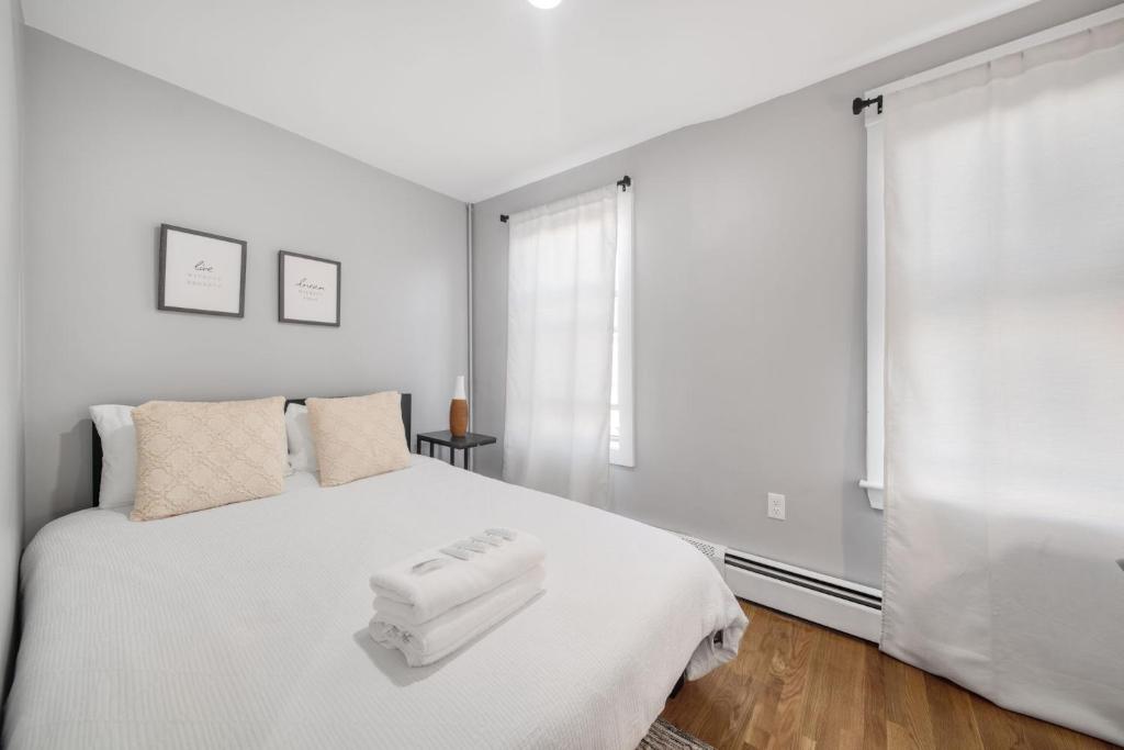 um quarto com uma cama branca com duas toalhas em 4BR1BTH South Boston Apt perfect for commutes em Boston