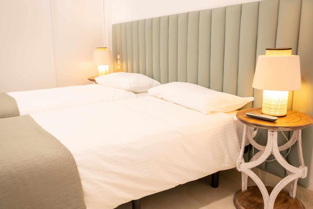 ein Schlafzimmer mit zwei Betten und einem Tisch mit Lampe in der Unterkunft Luxury Apartments Sabi Waikiki con garaje in Corralejo