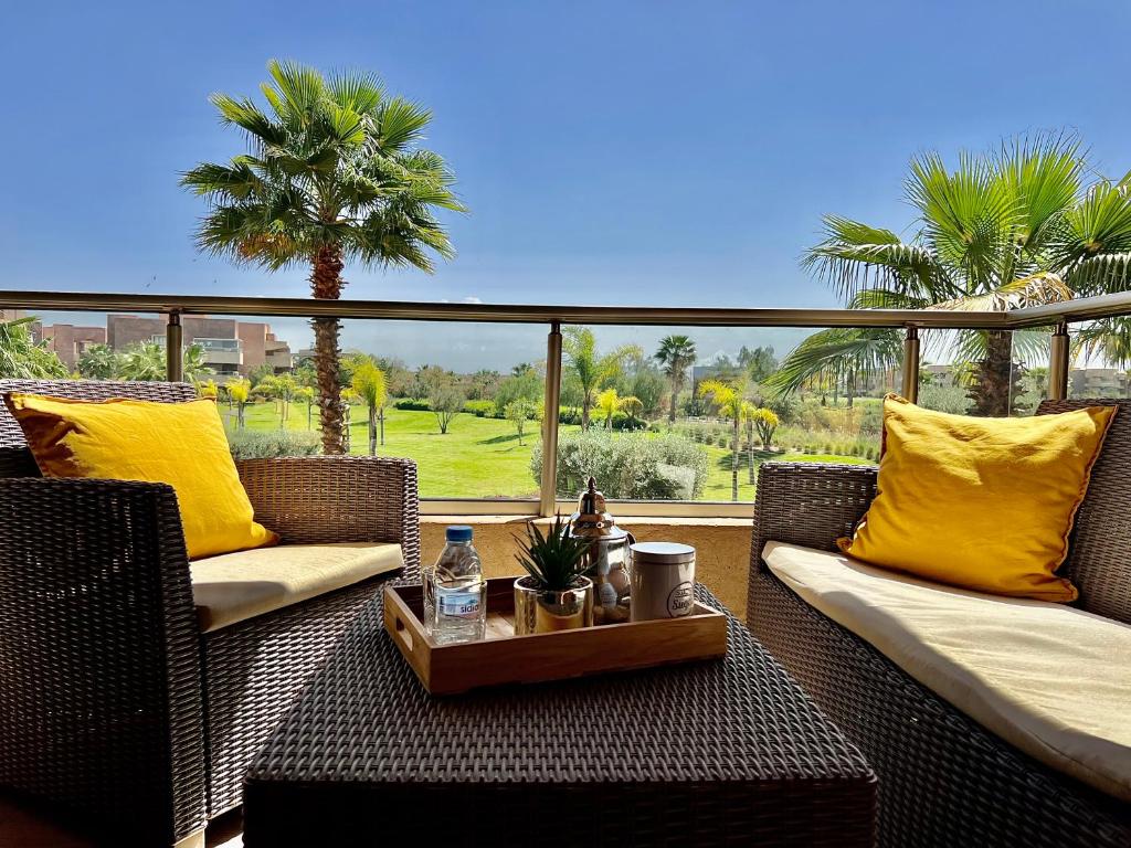 a porch with two wicker chairs and a table with a tray at Marrakech golf City prestigia in Marrakesh
