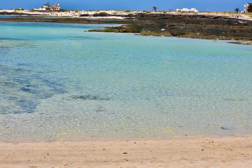 a beach with a body of blue water at Esmeralda Cotillo Homes by LIVVO in El Cotillo