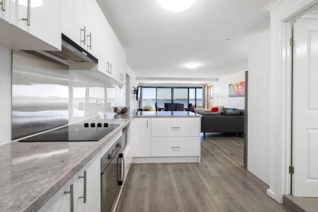 a kitchen with white cabinets and a living room at Almonta Apartments on the water front in Coffin Bay