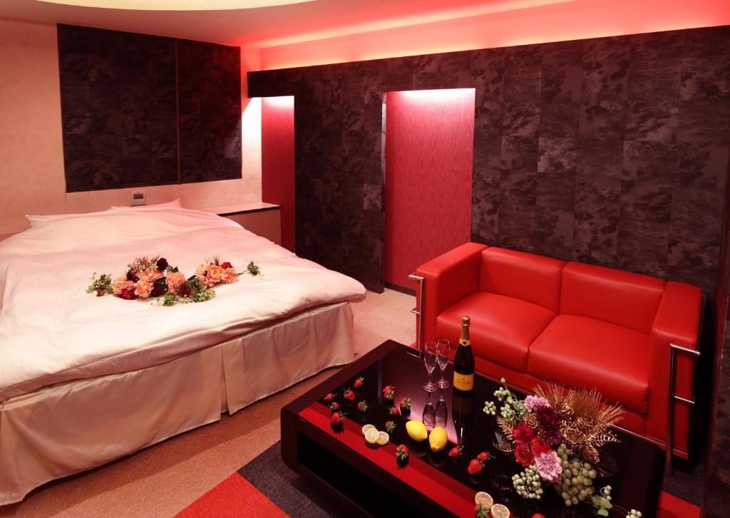 a hotel room with a bed and a red couch at 福井・鯖江のホテル｜ホテルモーメント in Sabae