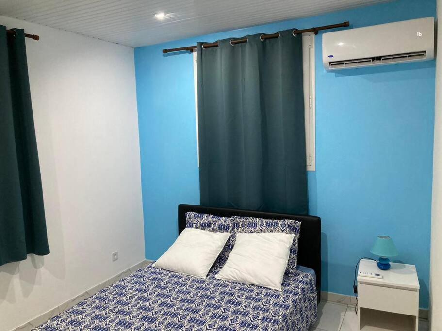 1 dormitorio con paredes azules y 1 cama con almohada en MAHOGANY, en Le Vauclin