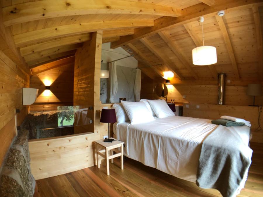 Cette chambre en bois comprend un grand lit. dans l'établissement Vila Alambique, à Bustelo