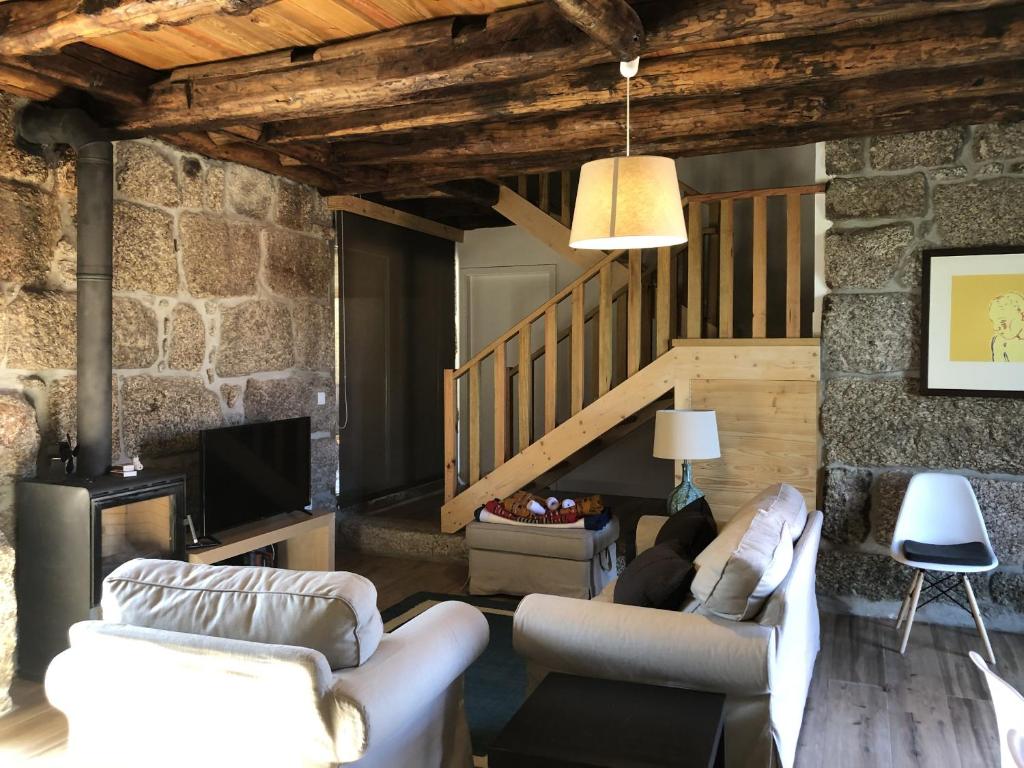 a living room with two couches and a staircase at Vila Forno in Bustelo