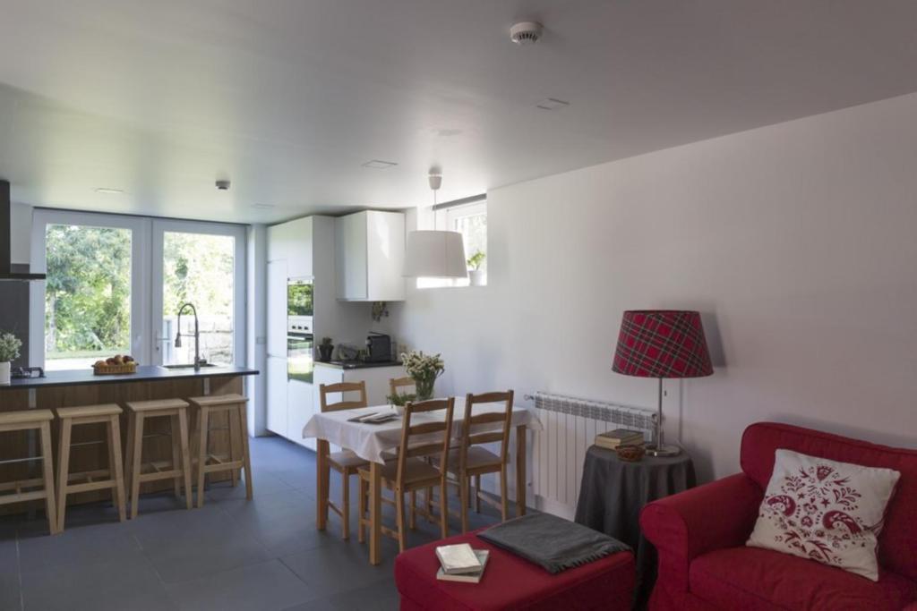 a living room with a red couch and a kitchen at Vila Lagar in Bustelo
