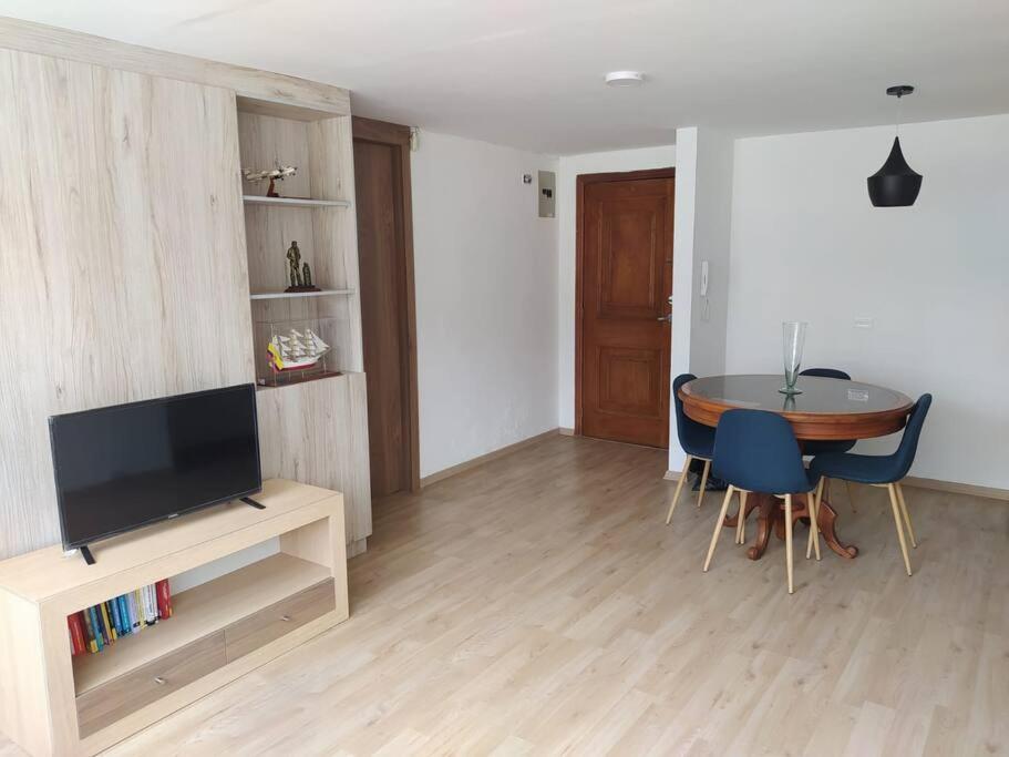 a living room with a table and a television at Acogedor Apartamento in Quito