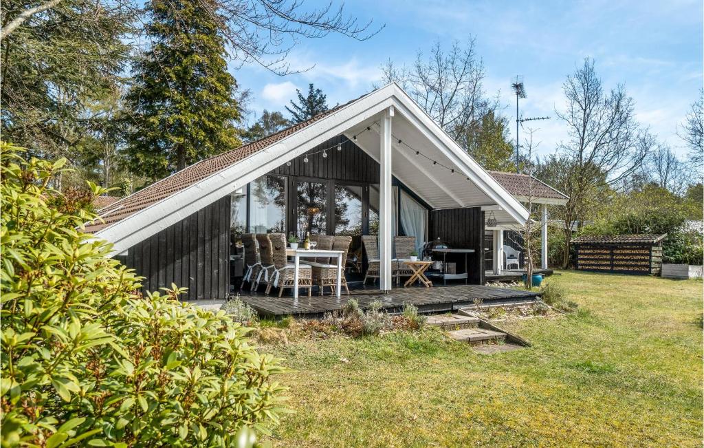 a black cottage with a white roof and a deck at 3 Bedroom Stunning Home In Hornbæk in Hornbæk