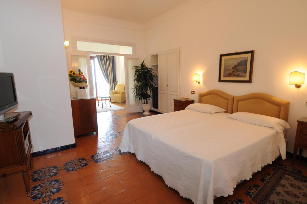 a bedroom with a white bed and a television at Hotel Belvedere in Conca dei Marini