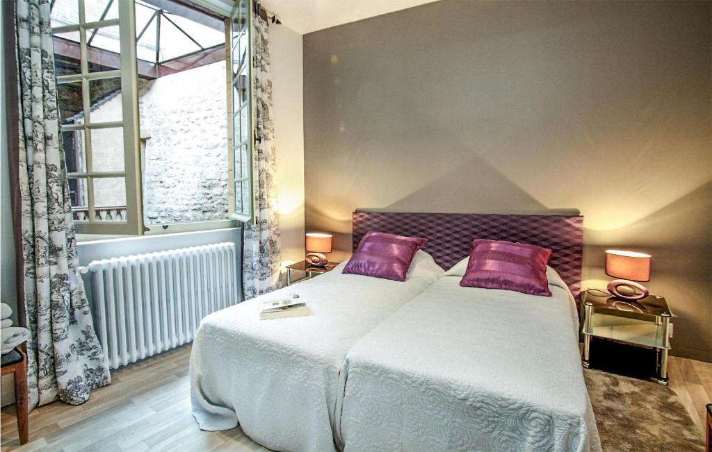a bedroom with a large white bed with purple pillows at Les 3 Oies in Sarlat-la-Canéda