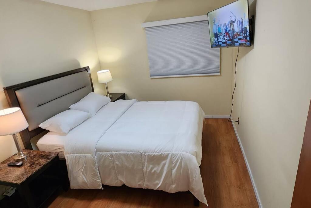 Schlafzimmer mit einem weißen Bett und einem Flachbild-TV in der Unterkunft Chesskings Guest House - Unit 2 in Winnipeg