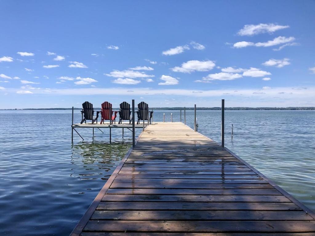 Paradise Waterfront Cottage (35 Min Drive From Toronto) في Georgina: ثلاثة كراسي جالسين على رصيف في الماء