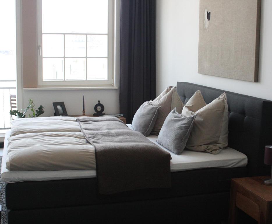 ein Bett mit Kissen darauf im Schlafzimmer in der Unterkunft Silentio Apartments in Leipzig