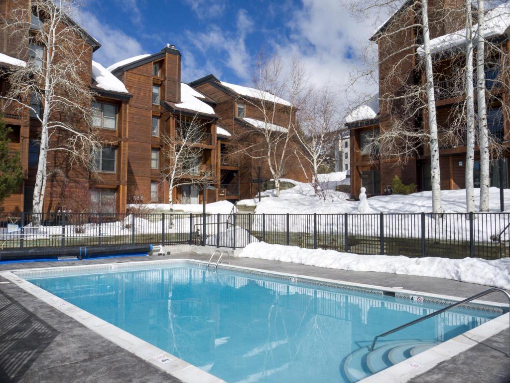 a swimming pool in front of a house with snow at Timber Run in Steamboat Springs