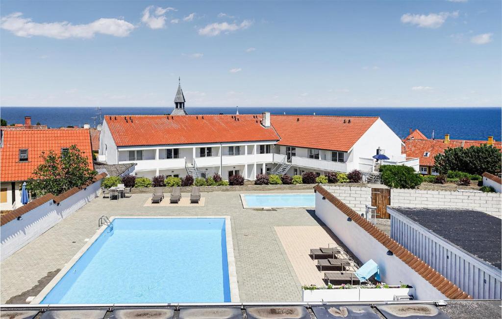 a house with a swimming pool in front of the ocean at Beautiful Apartment In Gudhjem With 1 Bedrooms, Wifi And Outdoor Swimming Pool in Gudhjem