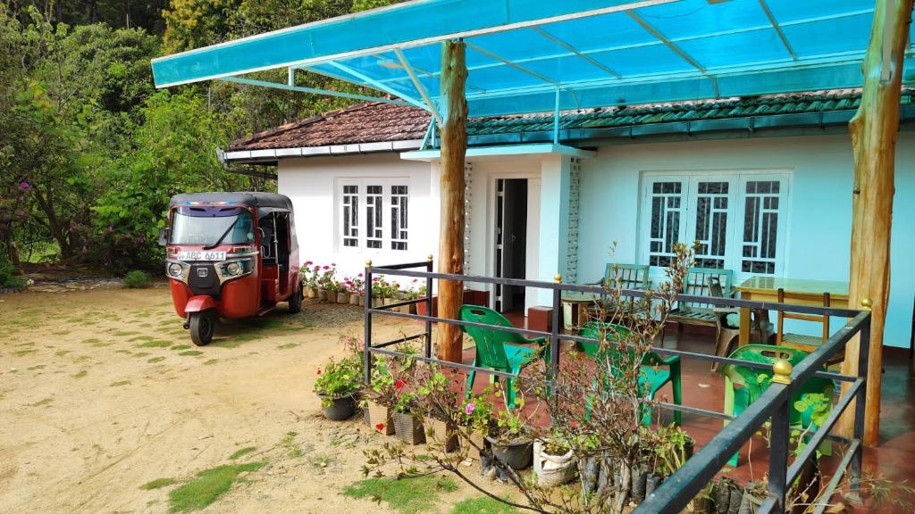 a small house with a red vehicle parked in front of it at Forest Cyniciam Homestay in Ohiya