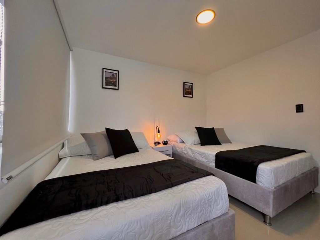 a bedroom with two beds and a lamp in it at Acogedor Moderno Tranquilo Wifi Disponible in Villamaría