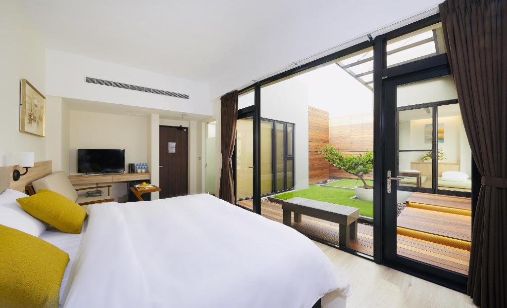 a bedroom with a large white bed and a balcony at Hotel Z in Taichung