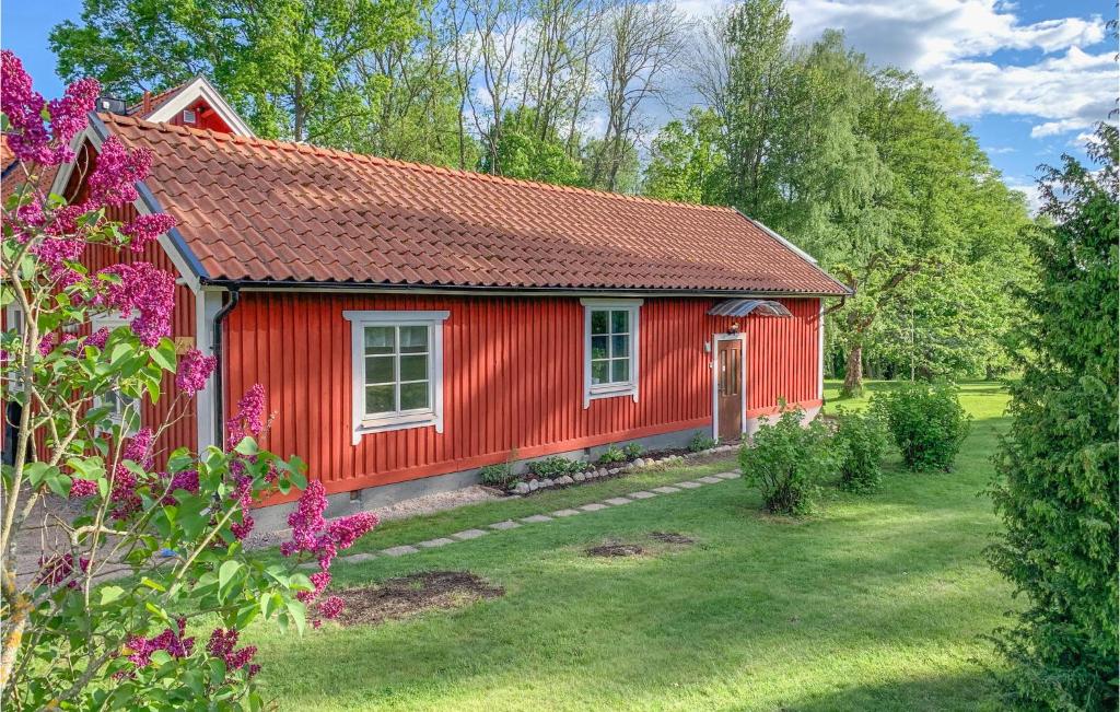 una casa roja en un jardín con flores púrpuras en Awesome Home In Vrena With Wifi en Vrena