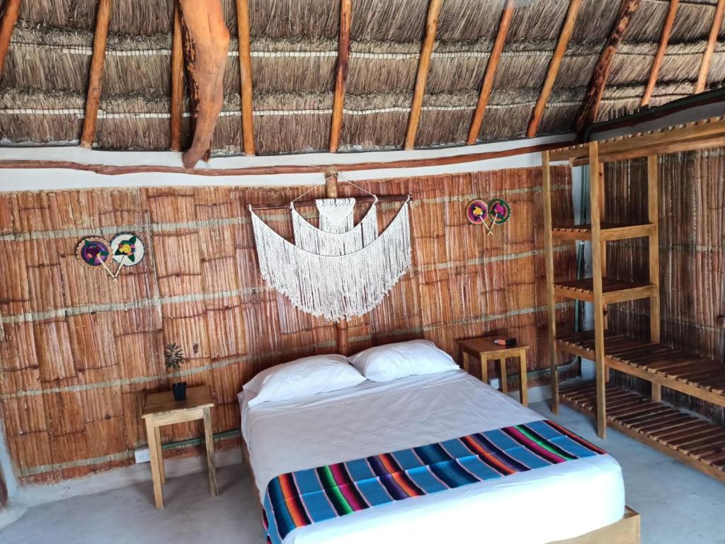 a bedroom with a bed in a thatched room at Cabañas Cinco Elementos in Celestún