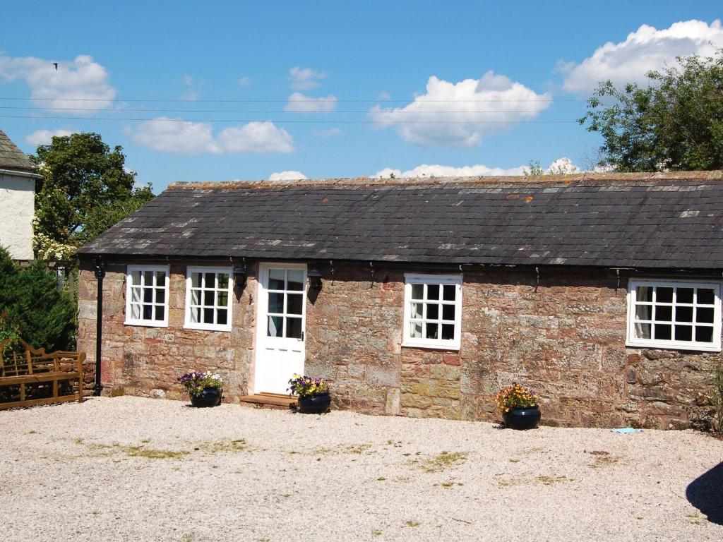 a small brick building with white windows and plants at Sycamore Cottage in Ellonby