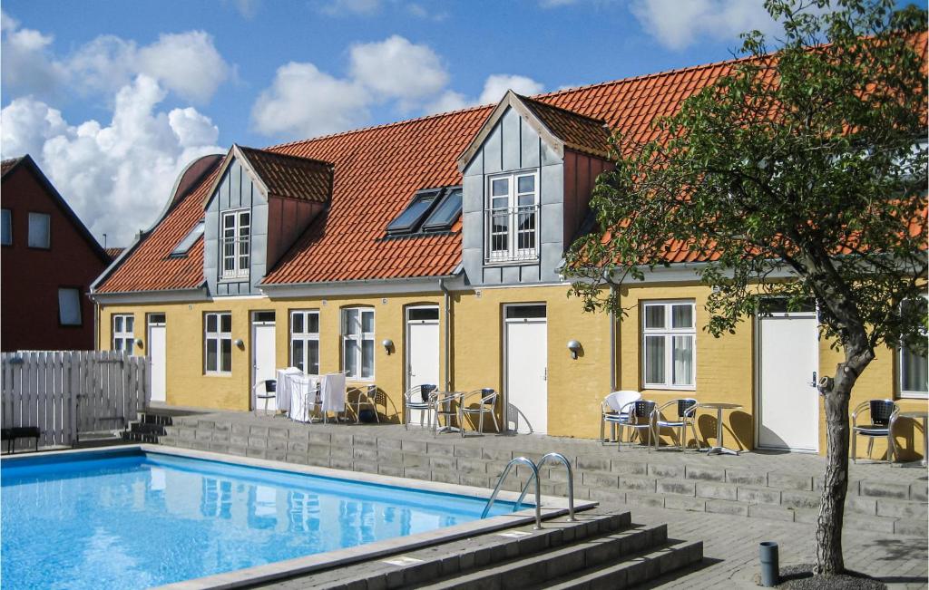 a house with a swimming pool in front of a house at Amazing Apartment In Gudhjem With 2 Bedrooms, Wifi And Outdoor Swimming Pool in Gudhjem