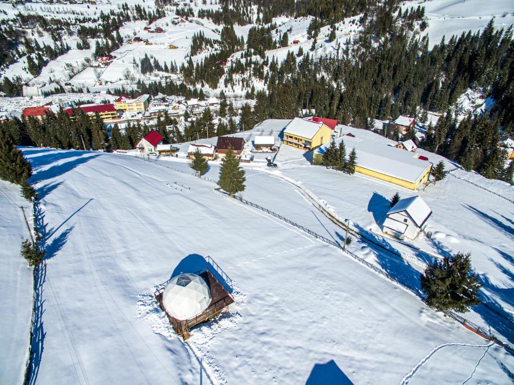 z góry widok na pokrytą śniegiem wioskę w górach w obiekcie WildGlampingArieseni w mieście Arieşeni