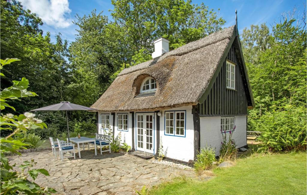 a cottage with a thatched roof and a table and chairs at 2 Bedroom Cozy Home In Gudhjem in Gudhjem