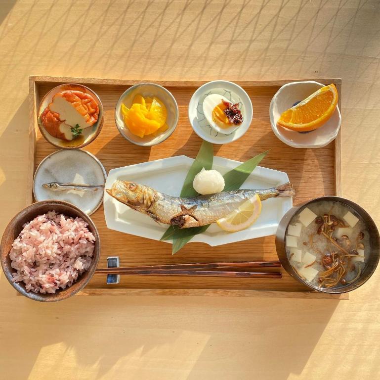 een dienblad met een bord vis en andere voedingsmiddelen bij Iwashi Building Hostel in Akune