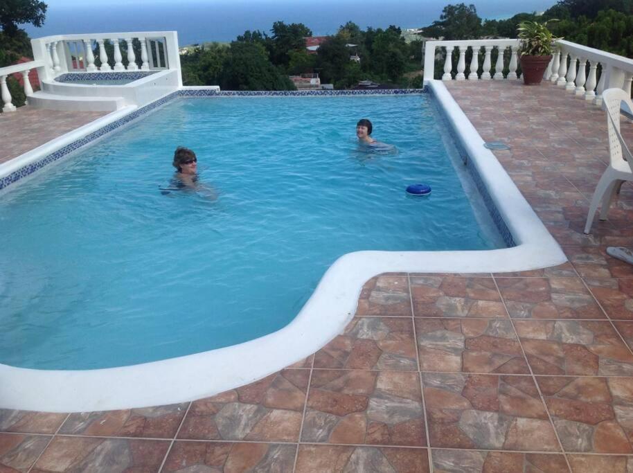 two people swimming in a swimming pool at Hibiscus Cottage in Belle Air Summit
