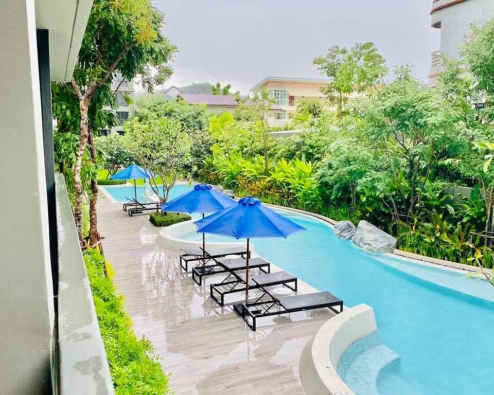 a pool with umbrellas and lounge chairs next to it at Pool View Marvest Huahin by Wilmot in Hua Hin