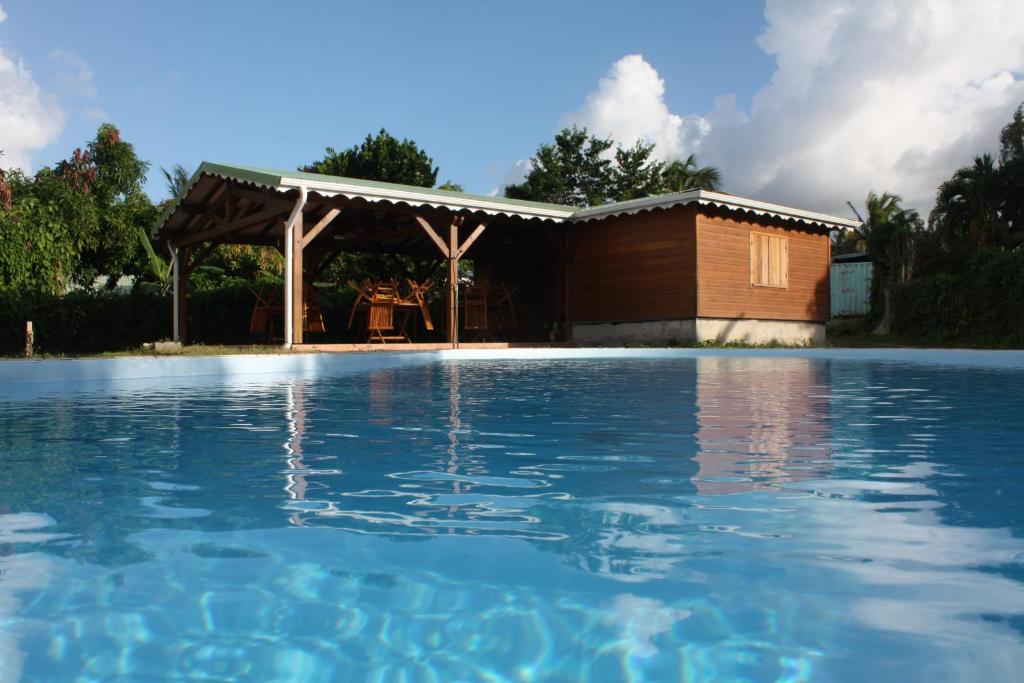 a swimming pool with a pergola and a house at Residences Guadeloupe in Sainte-Rose