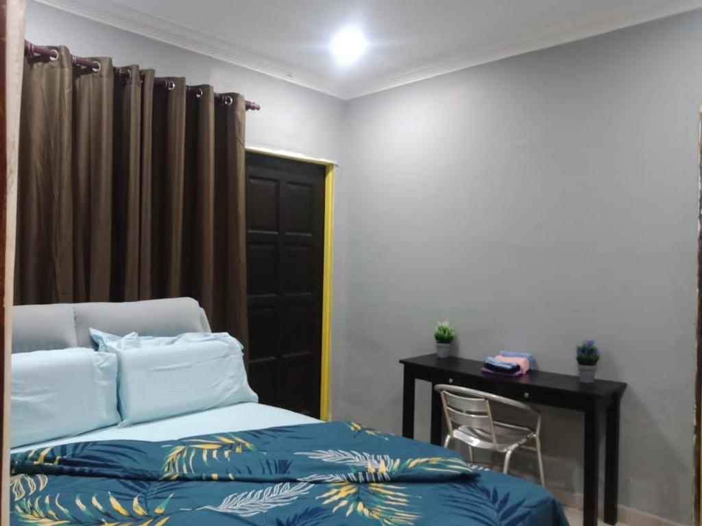 ein Schlafzimmer mit einem Bett und einem Schreibtisch mit einem Stuhl in der Unterkunft Kuntum Cottage Bad & Breakfast in Kampong Tanjong Ipoh