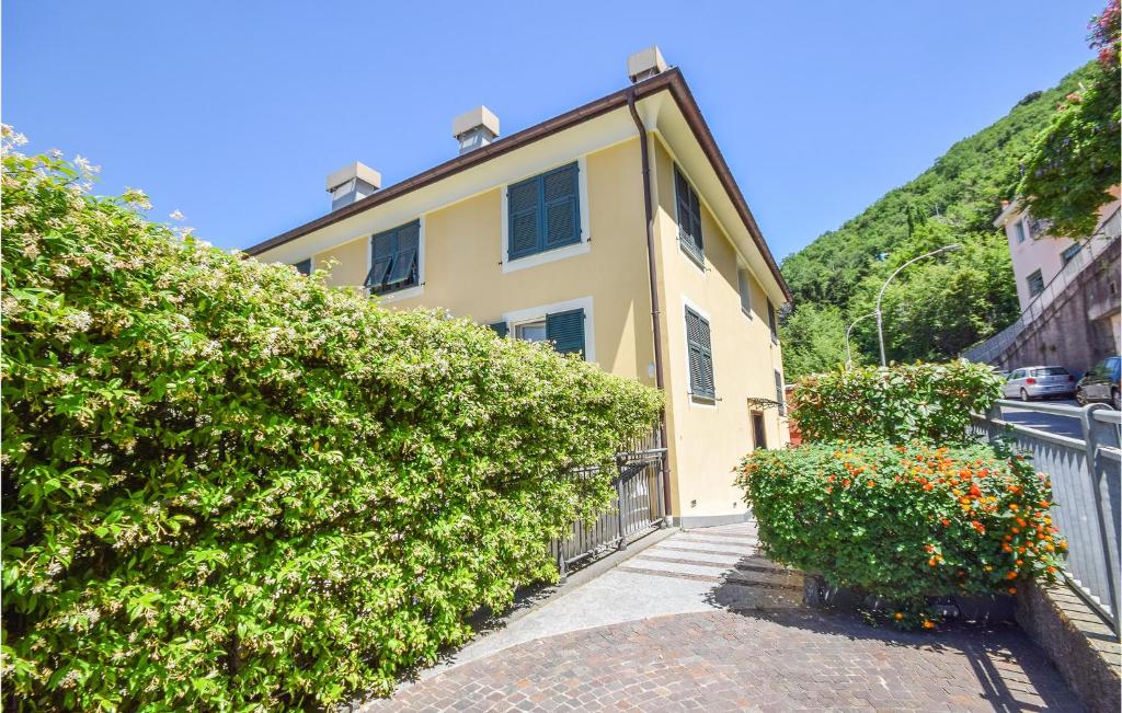 une maison jaune avec une haie à côté d'une rue dans l'établissement Stunning Apartment In Bogliasco With Kitchen, à Bogliasco