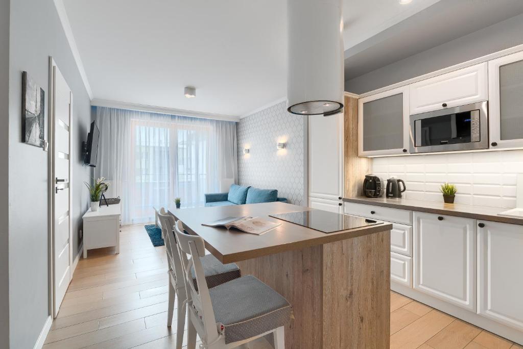 シュチェチンにあるEXCLUSIVE New Town Apartmentsの白いキャビネットとカウンタートップ付きの島が備わるキッチン