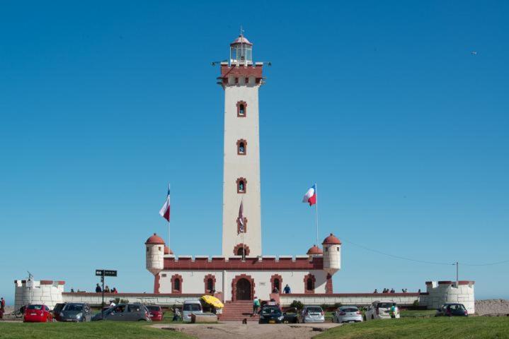 a lighthouse on top of a building with cars in front at Cabaña a pasos del Faro De La Serena in La Serena